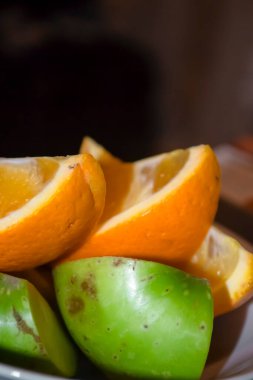 Doğranmış portakal ve elma. Tabakta doğranmış frizbiler var. Sağlıklı elma ve portakallar.