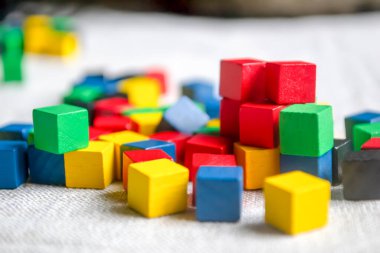 Çocuk küpleriyle dağılmış bir masa değil. Gri kumaş üzerinde renkli küpler. Yerde renkli çocuk küpleri var.. .