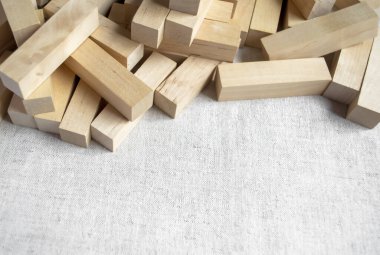 Kumaşın üzerindeki tahta parmaklıklar. Keten kumaşın üzerinde tasarımcının ahşap bloğu var. Çocuklar için yapılmış ahşap bir yapı seti masanın üzerinde duruyor. Oyun kulesinden tahta çubuklar.