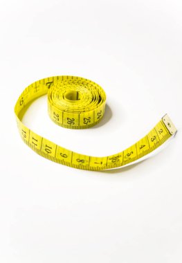 On the table is a long yellow ribbon with measurements for the seamstress. A yellow meter on a white background.