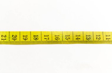 A yellow meter on a white background. On the table is a long yellow ribbon with measurements for the seamstress.