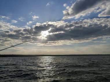 A bluebell for fishing rods on the background of the horizon. Roar - the sun sets. Fishing at sunset. Fishing rods in front of a beautiful horizon.