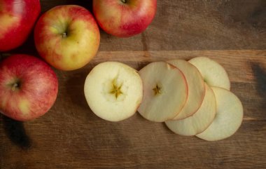 The apples are cut into rings on a wooden table. There are apple rings on the wood board. The fresh apple was cut into rings on the table.