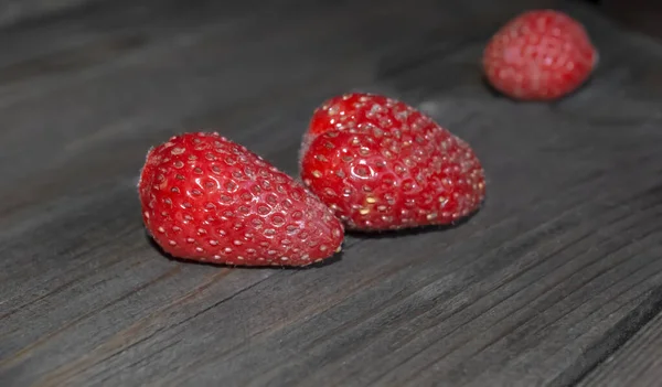 Schmutzige Erdbeeren Auf Dunklem Hintergrund Zwei Erdbeeren Auf Einem Holztisch — Stockfoto