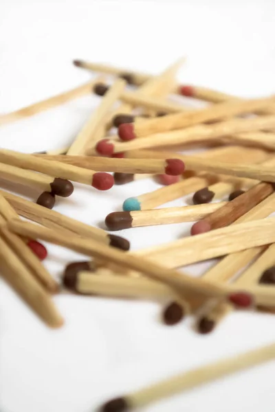 Lots of matches on a white background. an exception to the mass is a match with a different color. Matches with different colors on the heads. Among the matches, one blue one stands out.