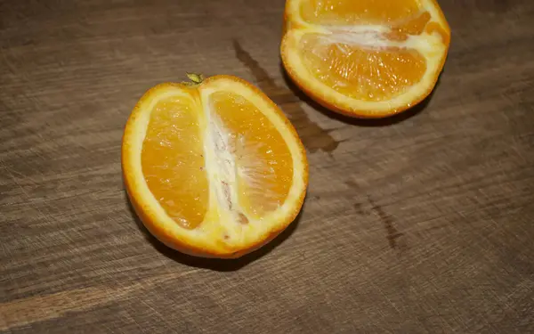 一半橙子躺在一张木制桌子上 是健康的柑橘类水果 船上躺着两半杯橙子 — 图库照片