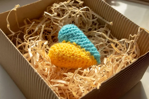 Knitted heart of yellow and blue flowers in a gift box. gift - the heart of the colors of the flag of Ukraine. The symbol of Ukraine is a yellow-blue heart in a gift box in tinsel.