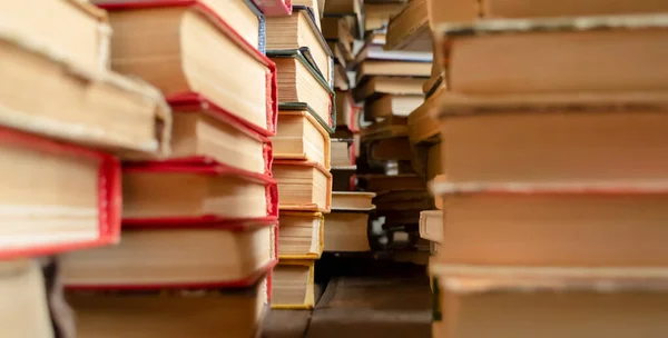 木製の床に本の行 多くの本が積み上げられている 古い本の列の間の通路 一箇所に多数の教科書が積まれている — ストック写真