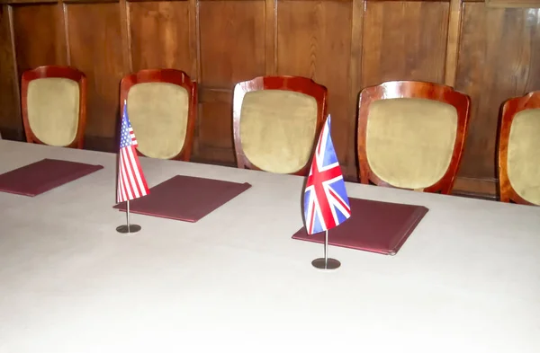 Moisture usa and England on the same table for negotiations next to folders. On the table is the flag of England and America.