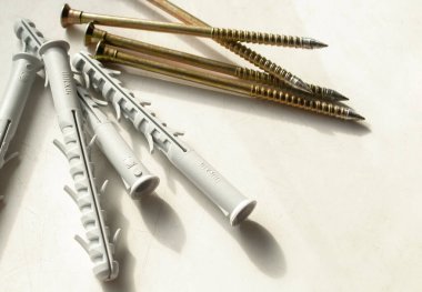 Hafif bir arka planda çember ve vidalar. Kirli, beyaz masada sarı vidalar ve gri paneller var. Yapı araçları.