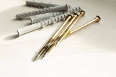 Hafif bir arka planda çember ve vidalar. İnşaat aletleri. Kirli, beyaz masada sarı vidalar ve gri paneller var..