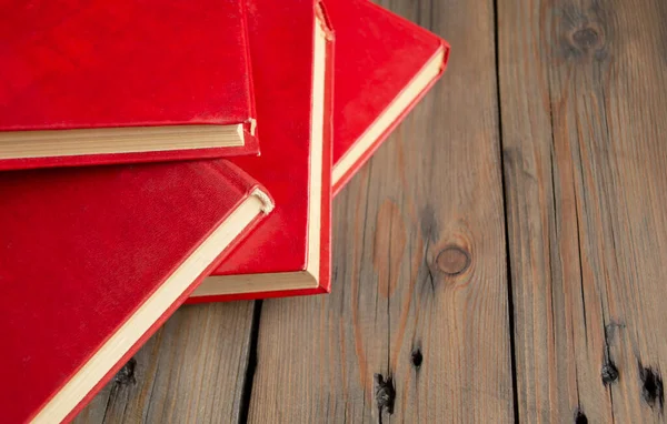 Books with a red cover on a wooden table. On a wooden background lies several books with a red cover. Textbooks for school and college.