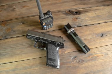 Bir telsiz, bir silah ve ahşap bir masada bir el feneri. Oyun takipçisi için aygıtlar. Silahlar ve askeri teçhizat.