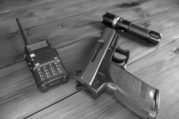 一个对讲机 一把枪和一个手电筒放在一张木制桌子上 武器和军事装备 游戏跟踪器的设备 黑人和白人 — 图库照片