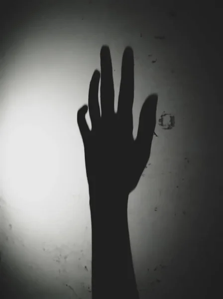 壁に手の影 古い壁を背景にぼんやりとしたエッジの光と影 恐ろしいコンセプトの写真は幽霊の手からのメッセージです — ストック写真
