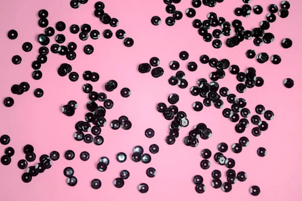 Black sequins on a pink background. black circles are scattered on pink. Pink background with black decorations.
