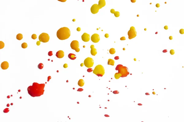 Spots of yellow and red paint on a white background. Drops of paint on a white canvas. Splashes of paint colored on white.