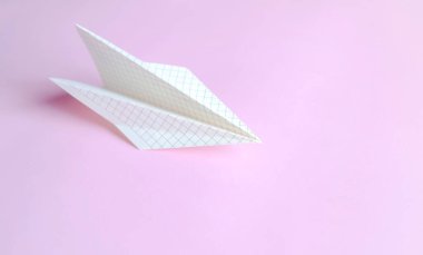Özgürlüğün ve yaratıcı uçuşun sembolü pembe üzerine kağıt bir uçak. Pembe arka planda bir kafeste kağıttan yapılmış uçak..