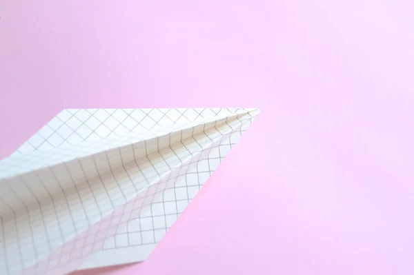 The symbol of freedom and creative flight is a paper plane on pink. Paper airplane made of paper in a cage on a pink background.