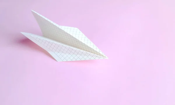 The symbol of freedom and creative flight is a paper plane on pink. Paper airplane made of paper in a cage on a pink background.