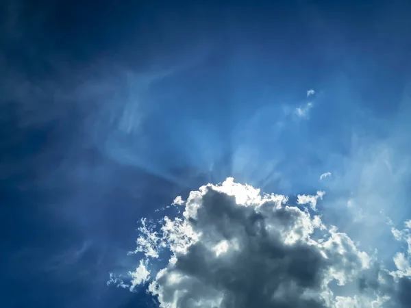 太陽は雲の後ろに隠れた 青い空には雲の後ろから太陽が昇る 雲が青い空に太陽を隠している — ストック写真
