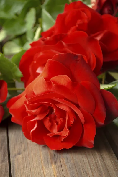 Červené Růže Leží Dřevěném Stole Stole Spousta Velkých Rudých Růží — Stock fotografie