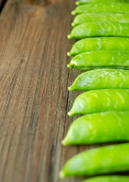 Yeşil Bezelye Kabukları Ahşap Bir Masanın Üzerinde Bir Sırada Yatıyor — Stok fotoğraf