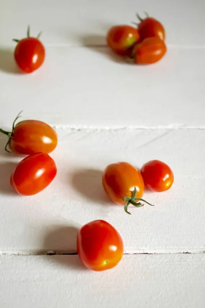 Red cherry tomatoes on a white table. fresh small tomatoes. Cherry tomato - a few pieces are on the table.