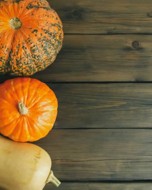 Tahta bir masada üç balkabağı. Sonbahar balkabakları Cadılar Bayramı süsüdür. Kabaklı satır kopyalama alanı.