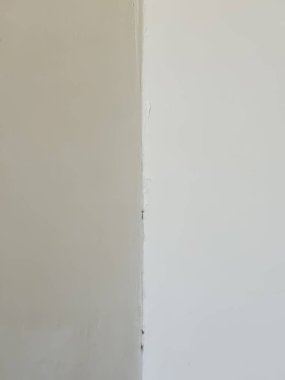 Odanın köşesinde. İki duvar arasındaki köşe. Beyaz duvar. Ortadaki köşe. Simetri.