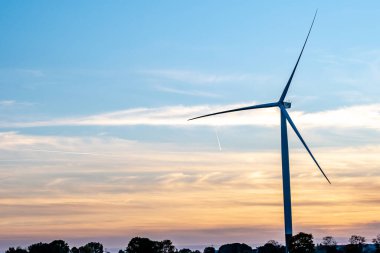 Gün batımında mavi ve turuncu gökyüzü olan bir fırıldak silueti.