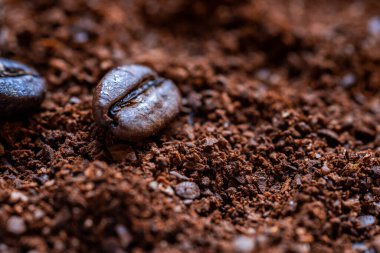 Taze kahve tozu ve iki kahve çekirdeğine yakın çekim.