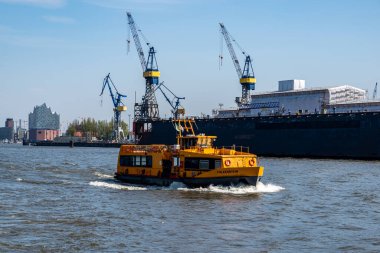 Hamburg, Almanya - 04 17 2023: Hamburg 'da bir feribotta su manzarası ve arka planda bir rıhtım ve elbphiharmoni var..