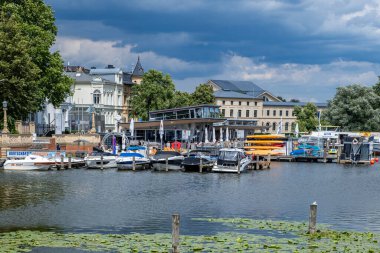 Schwerin, Mecklenburg-Vorpommern Almanya, 07 06 2023: Schweriner See 'den gelen su manzarası ve arka planda bir tekne rıhtımı ve eski evler.