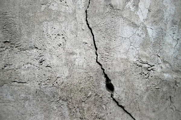 Duvarda bir delik olan dikey bir çatlak. Kumlu desenli eski beton yüzey.