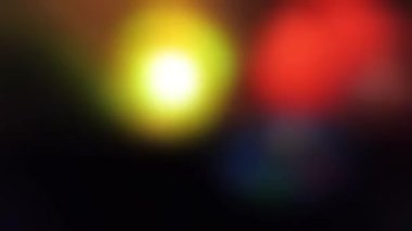 Siyah arka planda çok renkli ışıklar yanıp sönüyor. Neon ışık efektleri 4K 'da bulanık. Stok videosu.