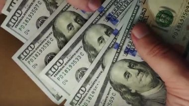 Bir adam yavaşça Amerikan dolarlarını sayıyor. Elinde Franklin 'in olduğu banknotlar. Bir sürü yüz dolarlık banknot. Tüm yüksek çözünürlüklü video kazançları.