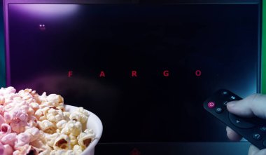 Kyiv. Ukrayna. 10.11.2023: Fargo serisini patlamış mısır ve uzaktan kumandalı biri izliyor. Stok editör fotoğrafı.