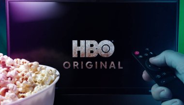Kyiv. Ukrayna. 10.11.2023: TV 'de patlamış mısır ve uzaktan kumandayla HBO' yu izleyen kişi. Stok editör fotoğrafı.