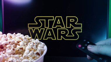 Kyiv. Ukrayna. 10.11.2023: Patlamış mısır ve uzaktan kumandalı Star Wars dizisi izleyen kişi. Stok editör fotoğrafı.