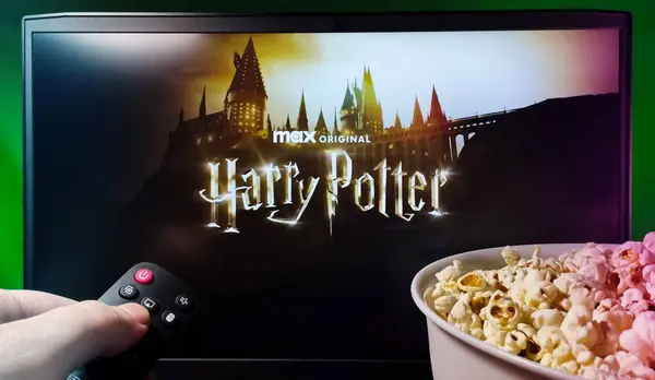Kyiv. Ukrayna. 11.12.2023: Patlamış mısır ve uzaktan kumandayla HBO Max 'te Harry Potter dizisini izleyen kişi. Stok editör fotoğrafı.