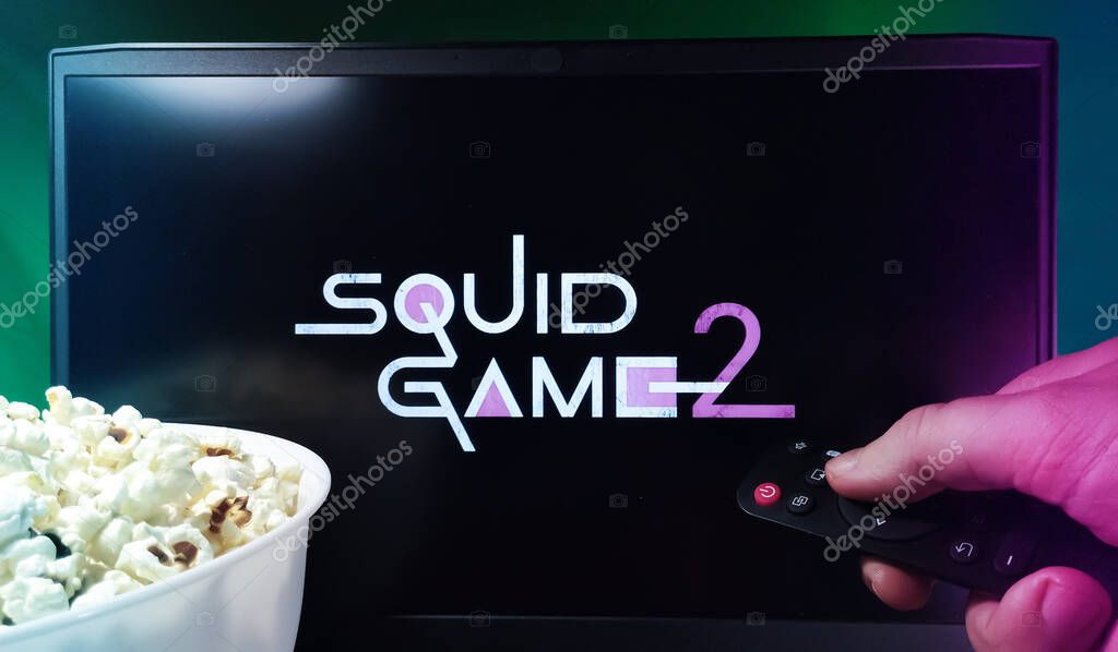 Person watching Squid Game 2 show with popcorn and a remote control. Stock editorial photo.
