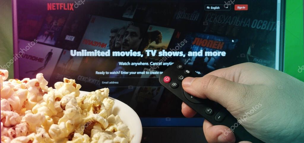 Kyiv. Ukraine. 10.11.2023: Person watching Netflix on TV with popcorn and remote control. Stock editorial photo.