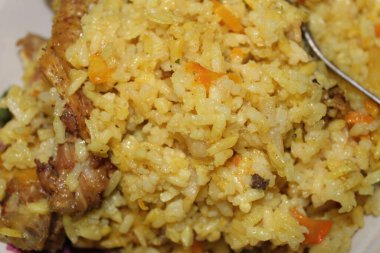 Renkli bir porsiyon sarı pirinç, taze kesilmiş sebzeler ve leziz tavuk parçaları gündelik bir ev mutfağında sunuluyor ve rahatlatıcı bir öğle yemeği elde ediliyor..