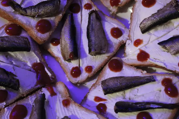 stock image Slices of bread are laid out with a spread of cream cheese topped with pieces of canned fish and ketchup droplets, creating an inviting dish at a casual get-together.