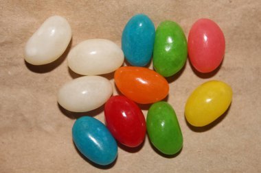 Değişik renkte ve aromalı jelibon koleksiyonu basit bir kahverengi kağıt yüzeyde düzenlenir ve şeker sevenlere tatlı bir hoşgörü sunulur..