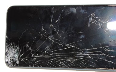 Akıllı telefonun ekranında geniş çatlaklar ve çizikler görülüyor, önemli bir çarpışma veya düşme sonrasında cihazların talihsiz durumu ortaya çıkıyor..