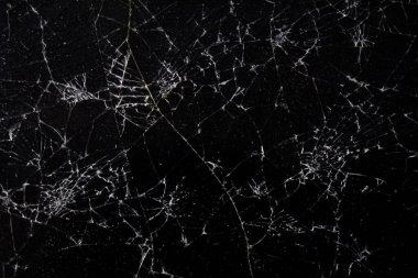 Karanlık bir yüzey, hasarın yol açtığı karmaşık desenleri vurgulayan ve zamanla aşınan karmaşık bir ağ şeklindeki çatlaklardan oluşur..