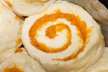 Freshly baked pumpkin cinnamon rolls rest on a cooling rack, displaying their warm, swirled filling of pumpkin and aromatic spices in a cozy kitchen. clipart