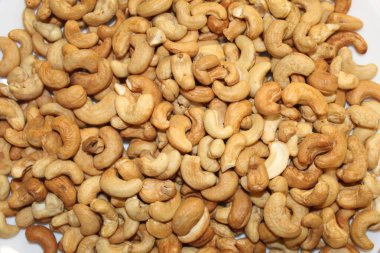 Değişik boyutlarda kaju fıstıkları ve dokular bir kaseyi doldurur. Parlak ışık altında doğal renk çeşitliliklerini ve benzersiz şekillerini gösterir..